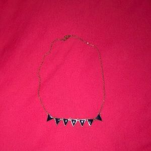 A gold necklace with navy triangles